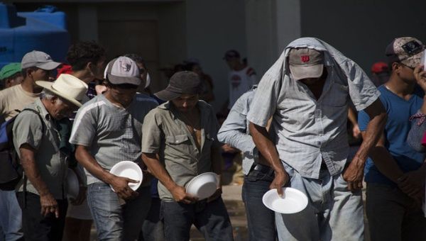 Integrantes de la caravana de migrantes centroamericanos que se dirigen a Estados Unidos hacen fila para recibir alimentos el municipio mexicano de Juchitán.