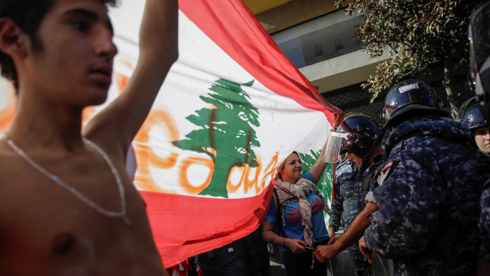 Manifestantes sostienen una bandera libanesa frente a los agentes de la policía durante las protestas en Beirut.