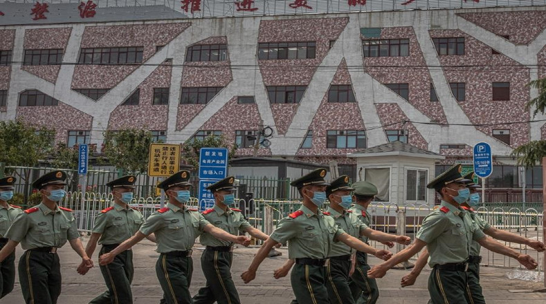 Xifandi, uno de los mercados más grandes de Beijing, fue cerrado el 13 de junio. Soldados chinos con mascarillas marchan junto al edificio cerrado.