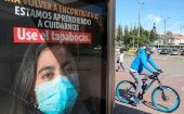 Un hombre circula en bicicleta junto a un anuncio que fomenta el uso del cubrebocas, en Bogotá, Colombia.
