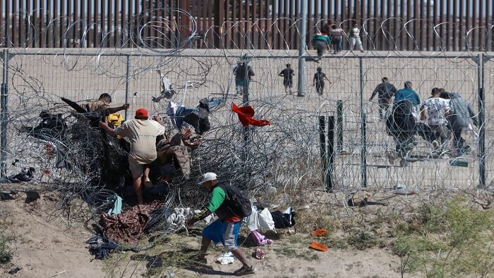 Migrantes atraviesan el muro que separa México de Estados Unidos, una de las fronteras más mortíferas del mundo.