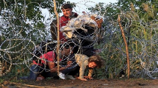 Esta familia siria intenta cruzar una valla de espino que separa a Serbia de Hungría. 
